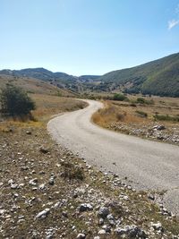 Dirt road amidst landscape against sky