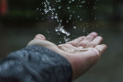Close-up of water falling on cropped hand