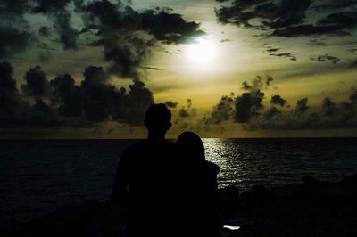 Silhouette of people in sea at sunset