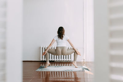 Rear view of woman sitting on chair against wall