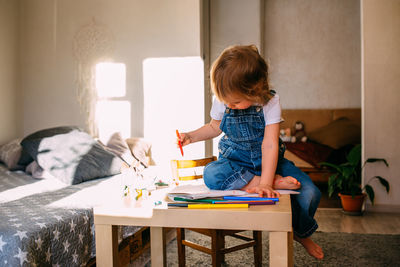 Small child at home at the children's table draws with felt-tip pens.