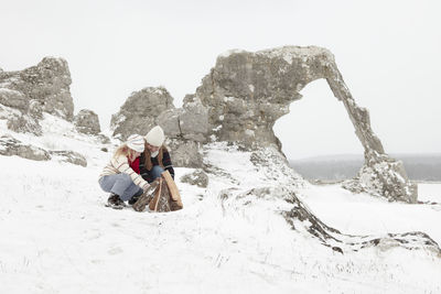 Mother with daughter making campfire at winter