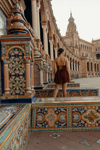 A young woman sitting in front of a historic building - plaza de espana. spanish square