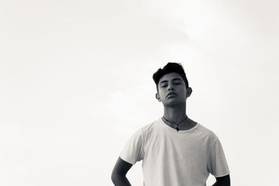 Portrait of young man looking away against sky