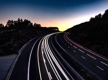 Road amidst trees against clear sky at night