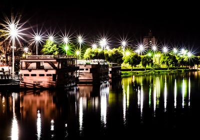 Illuminated bridge over river against sky at night