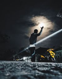 Man standing on illuminated road against sky at night