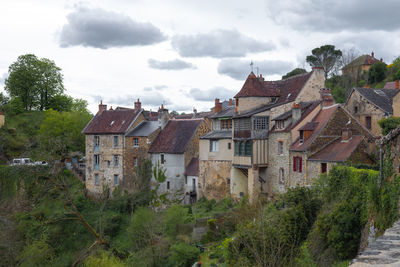 Houses amidst trees and buildings against sky