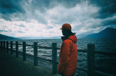 Rear view of man looking at sea against sky