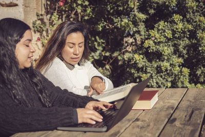 Portrait of young woman using laptop while sitting at park