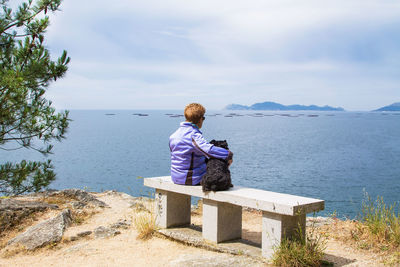 Lonely woman with her dog looking at the sea