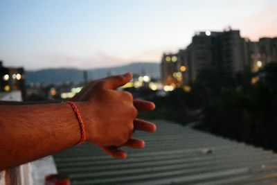 Close-up of person holding hands against sky