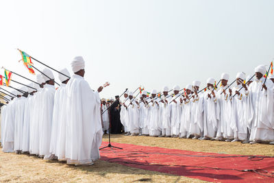 Rear view of people standing outside temple against sky