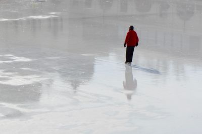 Full length rear view of man skating on ice rink