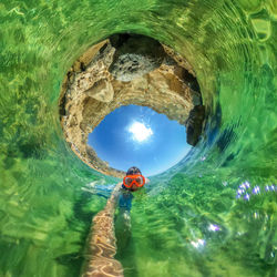 Man swimming in sea seen through tunnel