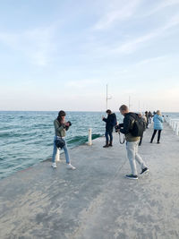 Men standing on beach against sky