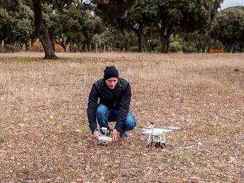 Man crouching by drone on grass