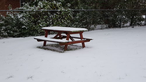 Chair on table against snow during winter