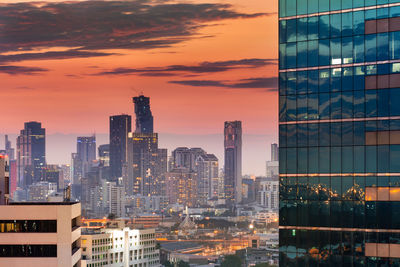 Illuminated cityscape against sky during sunset