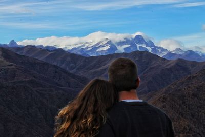 Rear view of couple looking at mountains against sky