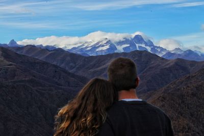 Rear view of woman looking at mountains against sky