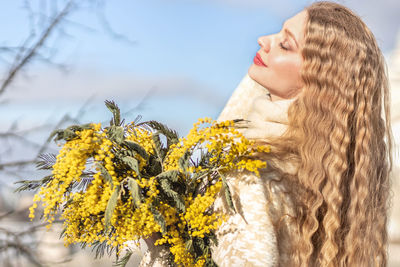 A woman with a bouquet of yellow acacia flowers. spring holiday - march 8, easter, women's day