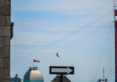 Low angle view of person on zip line against sky