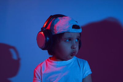 Cyberpunk boy child in a white t shirt and large headphones listening to music on the background