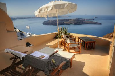 Scenic view of deck chairs and beach umbrella on terrace overlooking sea