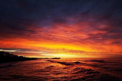 Scenic view of sea against cloudy sky at sunset