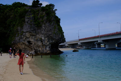 People on bridge over sea against sky