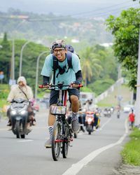 Rear view of man riding bycyle on road