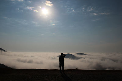 Rear view of man standing against cloudscape