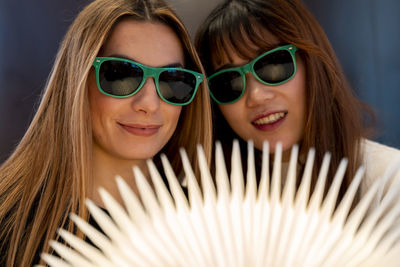 Multi-ethnic female couple of girlfriends are looking at a magical bright book indoors