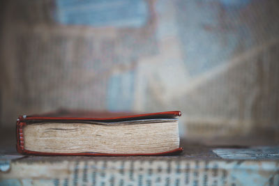 Close-up of open book on table against wall