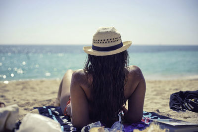 Rear view of woman relaxing on shore at beach