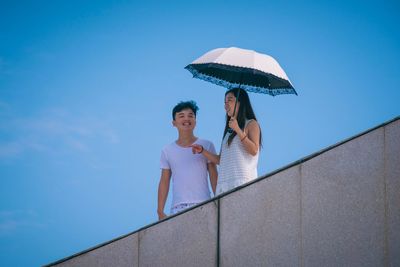 Low angle view of woman against blue sky