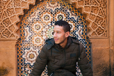 Smiling man looking away while sitting at historic place