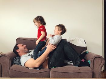 Father playing with children on sofa at home