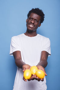 Portrait of man holding tomatoes on blue background