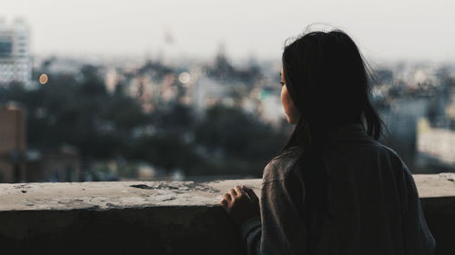 Rear view of woman in city against sky