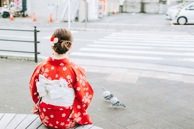 Rear view of woman in kimono sitting at city