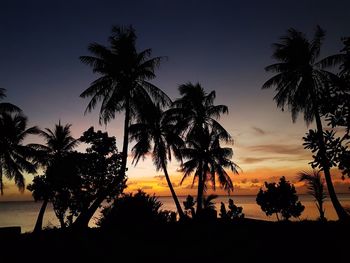 Silhouette palm trees on beach against sky at sunset