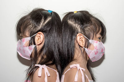 Side view of girls wearing mask against white background
