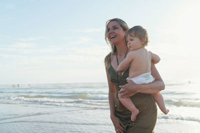 Mother and son on beach against sky