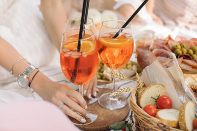 Woman holding summer cocktail on picnic in the park. birthday celebration outdoors.