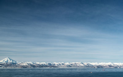 Scenic view of sea amidst snowcapped mountains against sky