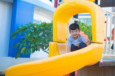 Happy boy playing on slide in playground