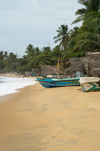 Boat moored on beach against sky