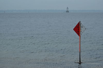 Close-up of red flag on sea against sky